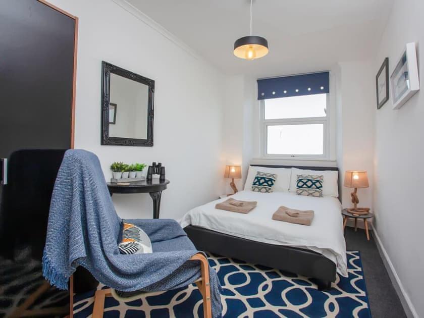 a bedroom with a bed and a chair and a window at Large House, sleeps 10 with incredible sea views in Ilfracombe