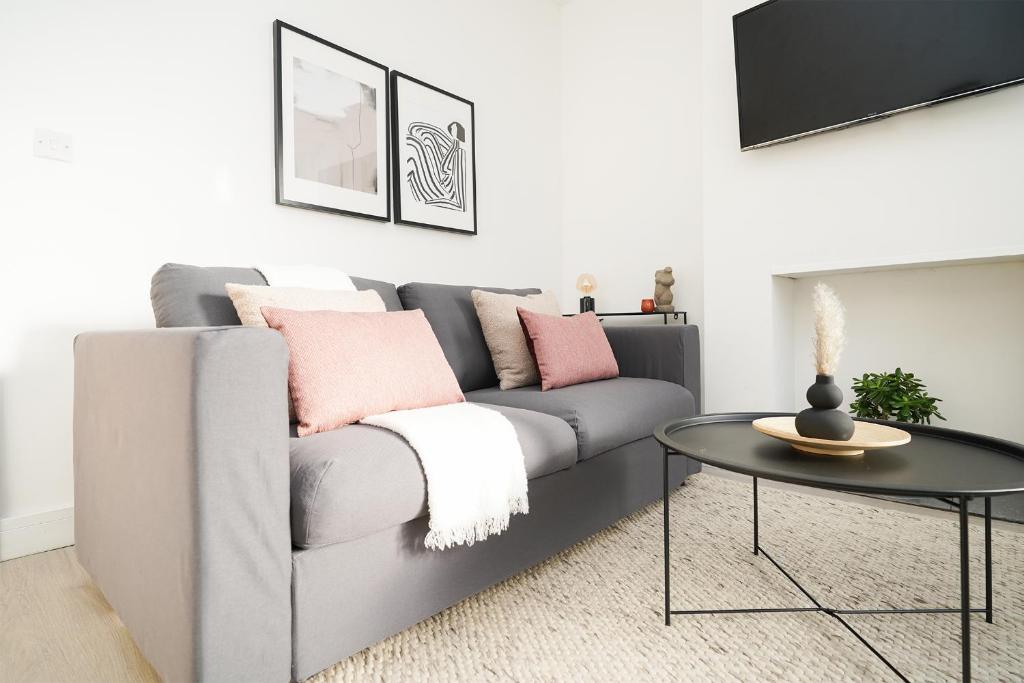 a living room with a grey couch with pink pillows at Charlotte House, entire private house, close to city centre, WiFi in Sheffield