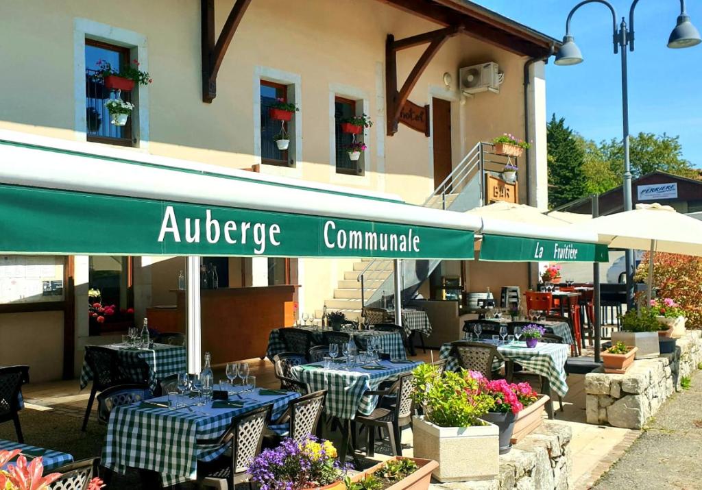 restauracja ze stołami i krzesłami przed budynkiem w obiekcie Auberge Communale de la Fruitière w mieście Péron