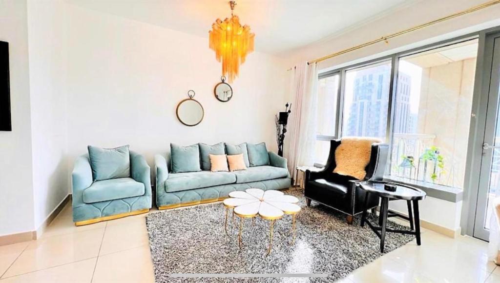 un salon avec un canapé bleu et une chaise dans l'établissement Lovely 1 Bedroom Luxury Apartment next to Burj Khalifa!! 24hr Concierge, Gym, Pool & Netflix - 29 Burj Boulevard in the heart of Downtown, à Dubaï