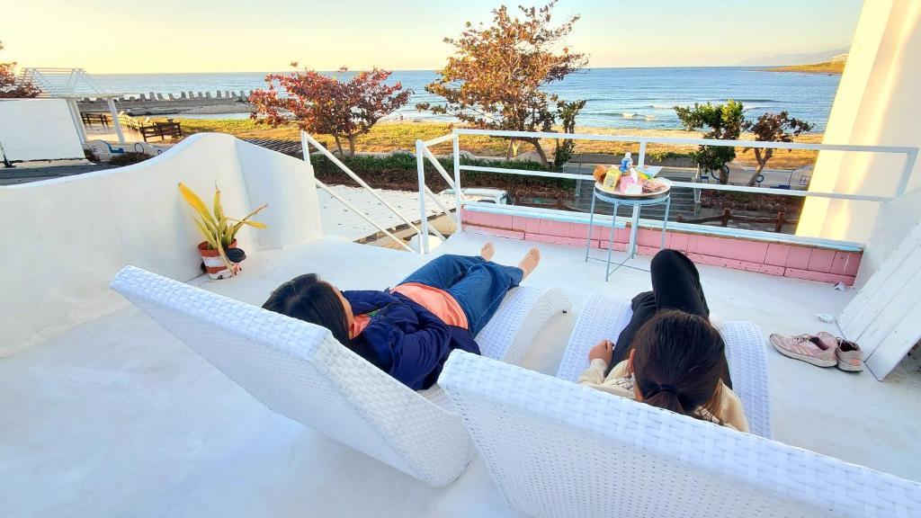 車城鄉的住宿－墾丁後灣 米夏小白屋海景包棟Villa，两个孩子躺在阳台上,一边欣赏海景