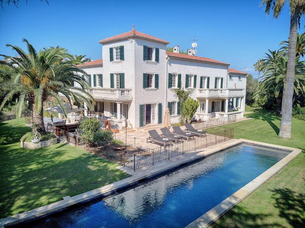 una casa grande con piscina frente a ella en LE BEAUVERT Belle Epoque luxury villa of 500 m2 with pool, en Antibes