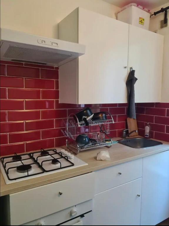 uma cozinha com um fogão e uma parede de tijolos vermelhos em F2 au cœur de Paris em Paris