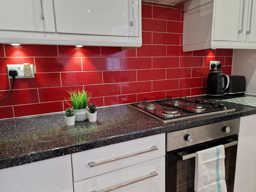 a kitchen with a red tiled wall at Newly Furnished Close to City Centre in Hunslet