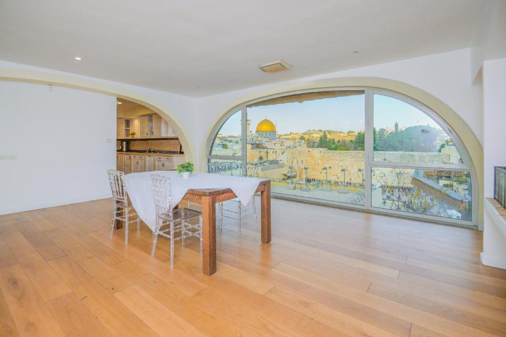 een eetkamer met een tafel en een groot raam bij Western Wall View Apartment in Jeruzalem