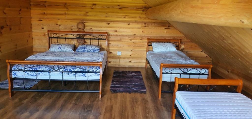 1 dormitorio con 2 camas en una cabaña de madera en Drulenu sodyba, 