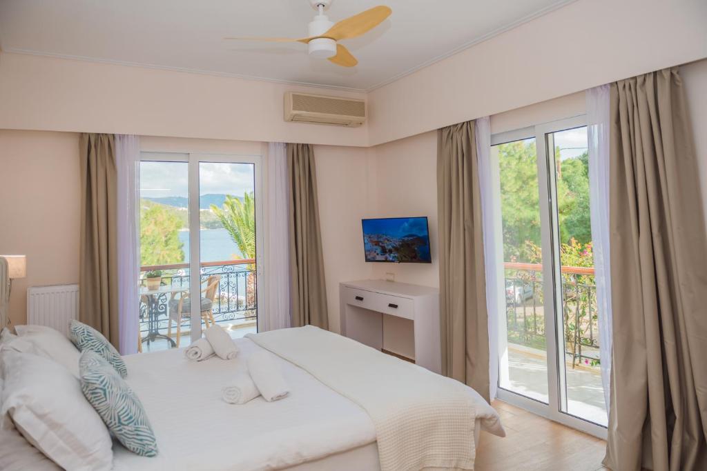 a bedroom with a white bed and a balcony at Philoxenia Ganossis in Ermioni
