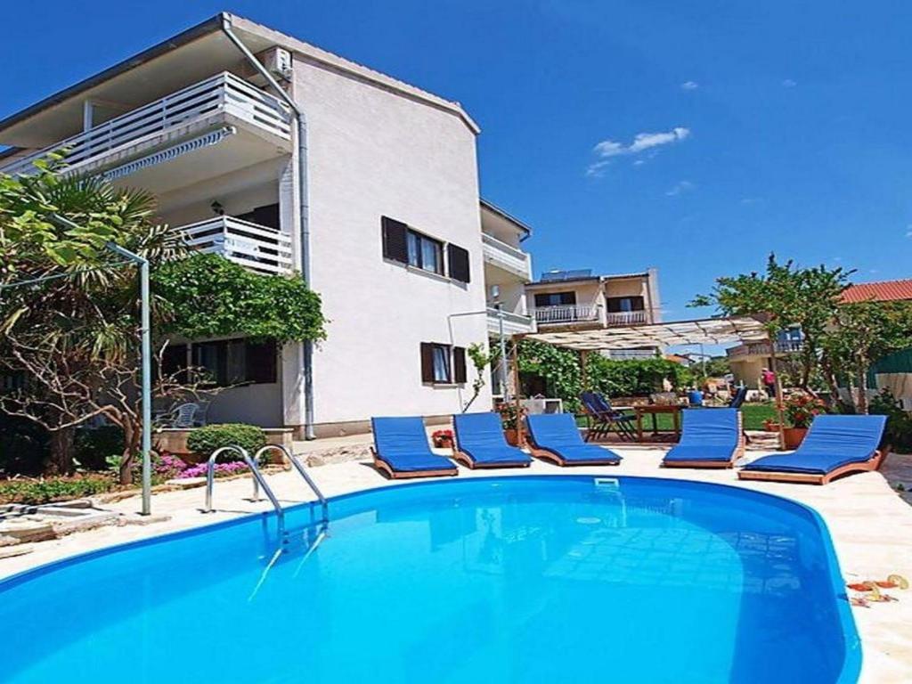 una piscina con sillas y una casa en Apartments Zadro, en Tribunj