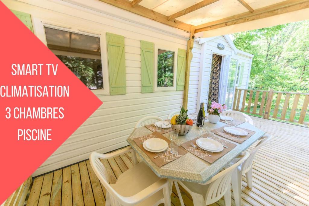une table et des chaises sur une terrasse dans une maison dans l'établissement Mobil-home LE WILSON, à Mirgaudon