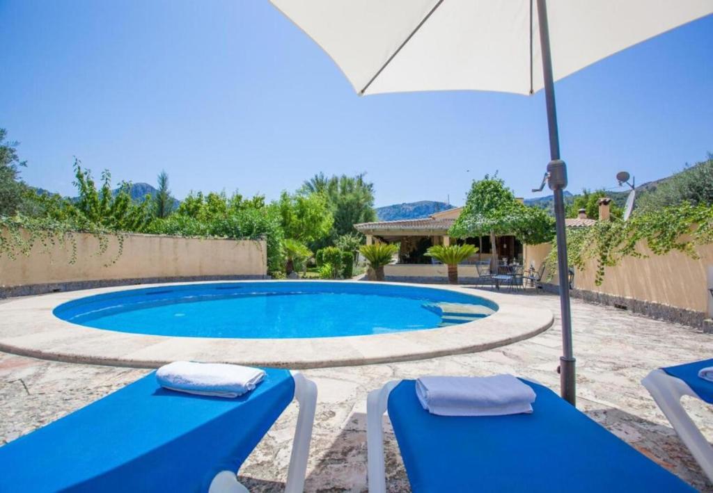 een zwembad met twee blauwe stoelen en een parasol bij Finca Sa Sort Llarga in Pollença