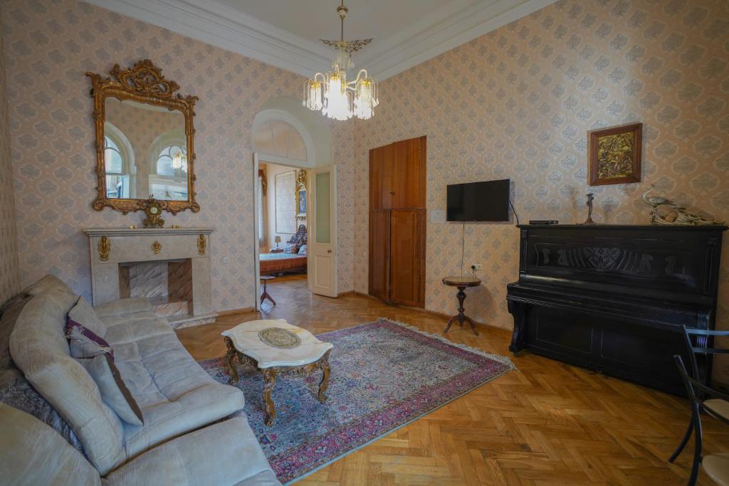 a living room with a couch and a mirror and a piano at Leon Rooms in Tbilisi City