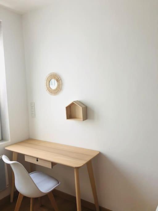 a wooden desk with a white chair next to a wall at Appartement A confortable et lumineux in Neufchâtel-Hardelot