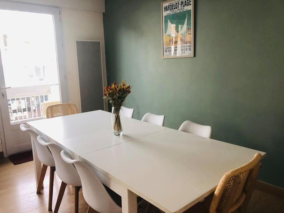 a white table with chairs and a vase of flowers on it at Appartement A confortable et lumineux in Neufchâtel-Hardelot