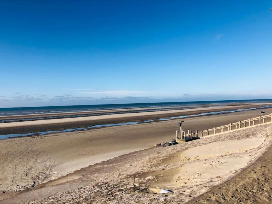 a sandy beach with a fence and the ocean at Appartement A confortable et lumineux in Neufchâtel-Hardelot