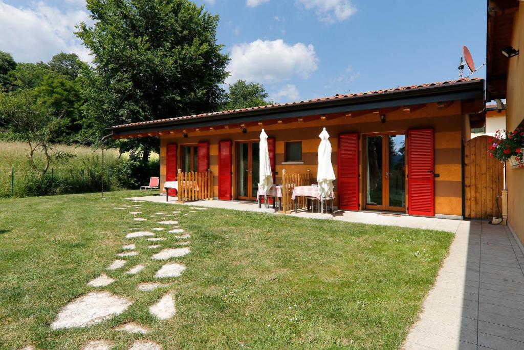 een rood huis met een tafel en stoelen in een tuin bij Agriturismo Terra e Lago d'Iseo Franciacorta in Paratico