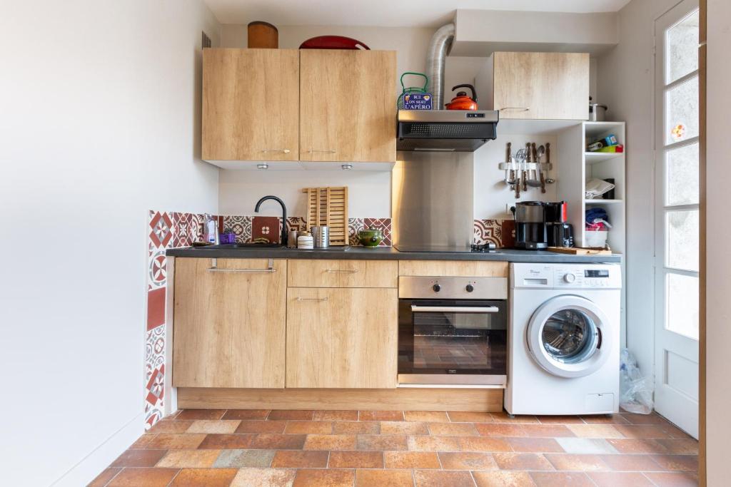 - une cuisine avec des placards en bois et un lave-linge/sèche-linge dans l'établissement Chalet Les Noisetiers, à Saint-Lary-Soulan