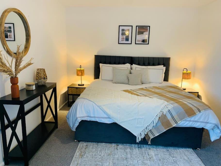 a bedroom with a large bed and a mirror at 2Bed Annexe nr Vale Resort, Golf & Spa in Ystradowen