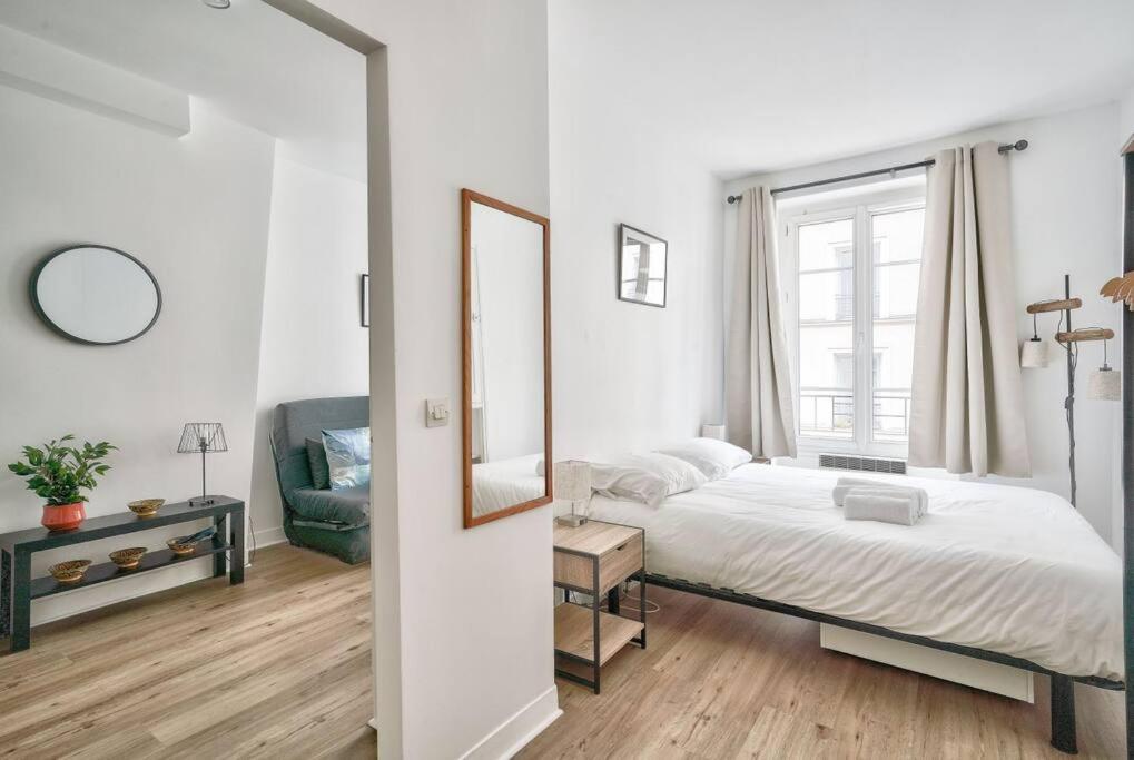 une chambre blanche avec un lit et un miroir dans l'établissement Nice 1 BR Flat 10 min from Place de la Bastille, à Paris
