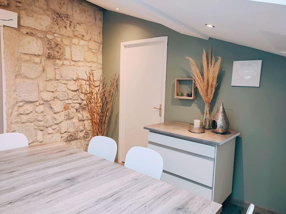 Maison chaleureuse située à Saumur في سوموور: غرفة طعام مع طاولة وكراسي وجدار حجري