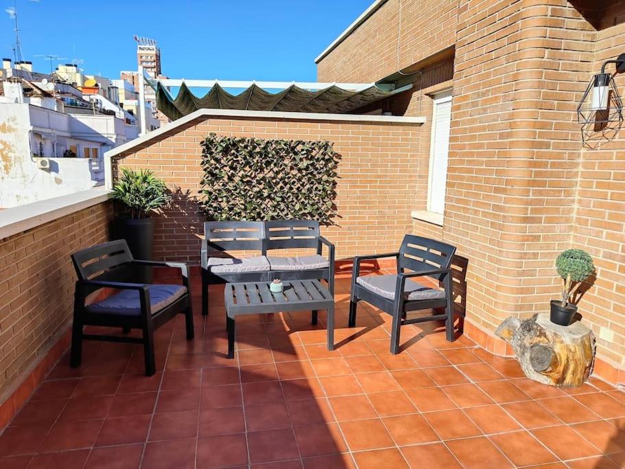 d'une terrasse avec une table et des chaises sur un mur en briques. dans l'établissement APARTAMENTOS TURISTICOS SEVIRO Madrid, à Madrid