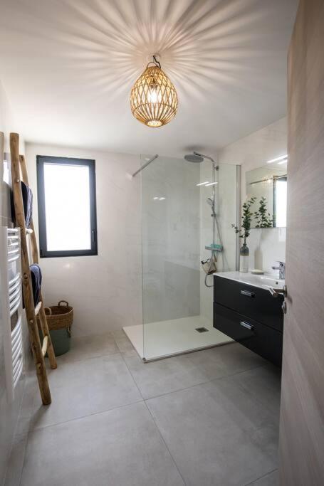 a bathroom with a shower and a sink and a chandelier at Stanatura Appt 2 chambres vue panoramique #INDENO in Porto-Vecchio