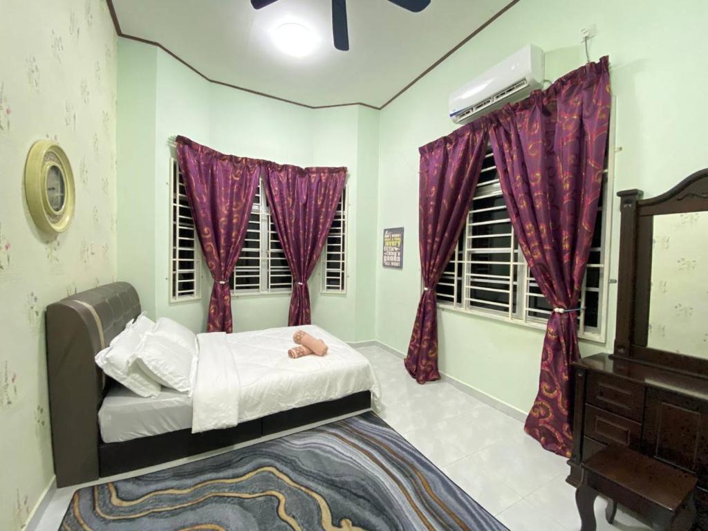 une chambre avec un lit avec des rideaux violets et une commode dans l'établissement Homestay Affan03 Gong Badak Dekat UNISZA & 500 meter dari Pantai, à Kampong Tanjong Gelam