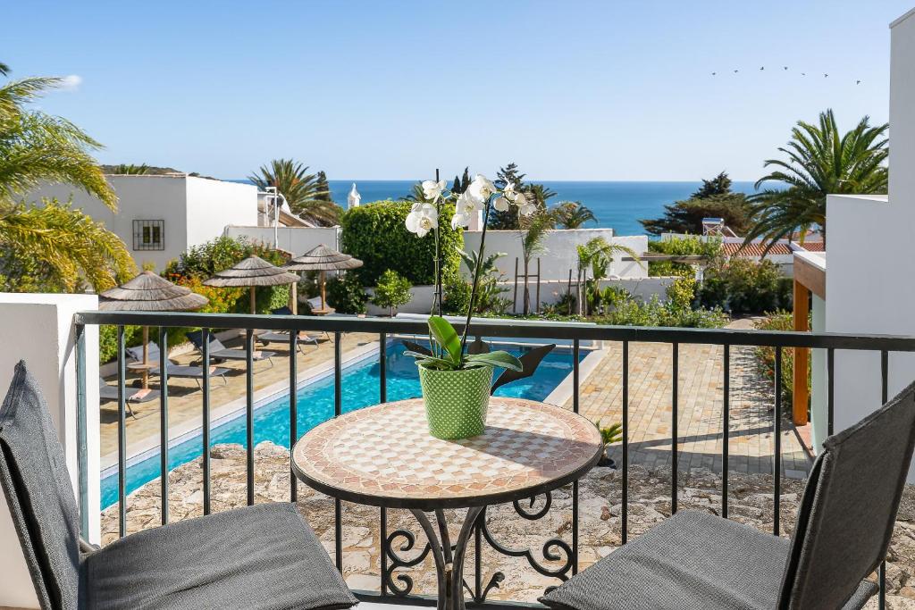 balcón con mesa, sillas y piscina en Romantik Villa, en Salema