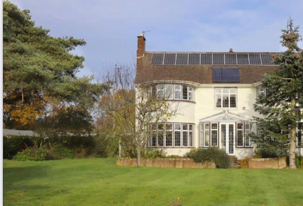 una gran casa blanca con paneles solares en el techo en Valesmoor Farm en New Milton
