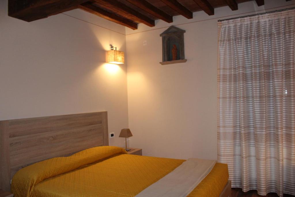 a bedroom with a yellow bed and a window at Albergo Da Ca' Vecia in Spilamberto