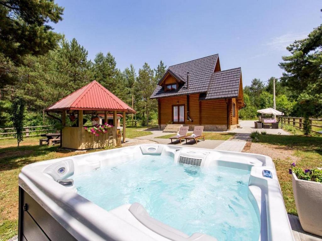 a hot tub in front of a log house at Apartments Plitvice forest in Korenica