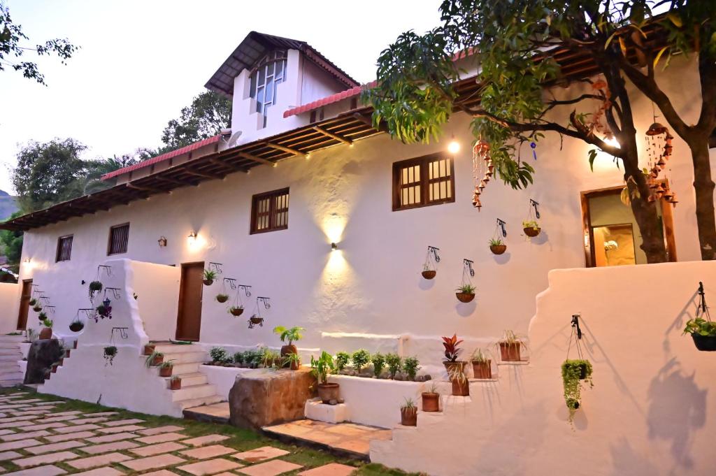 a white house with potted plants on the facade at Achalaa Resort in Kolhapur
