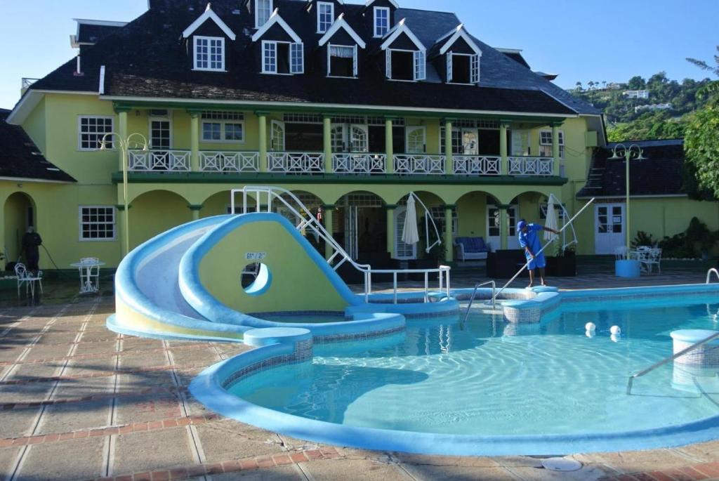a pool with a slide in front of a house at Deluxe SandCastles Condos in Ocho Rios
