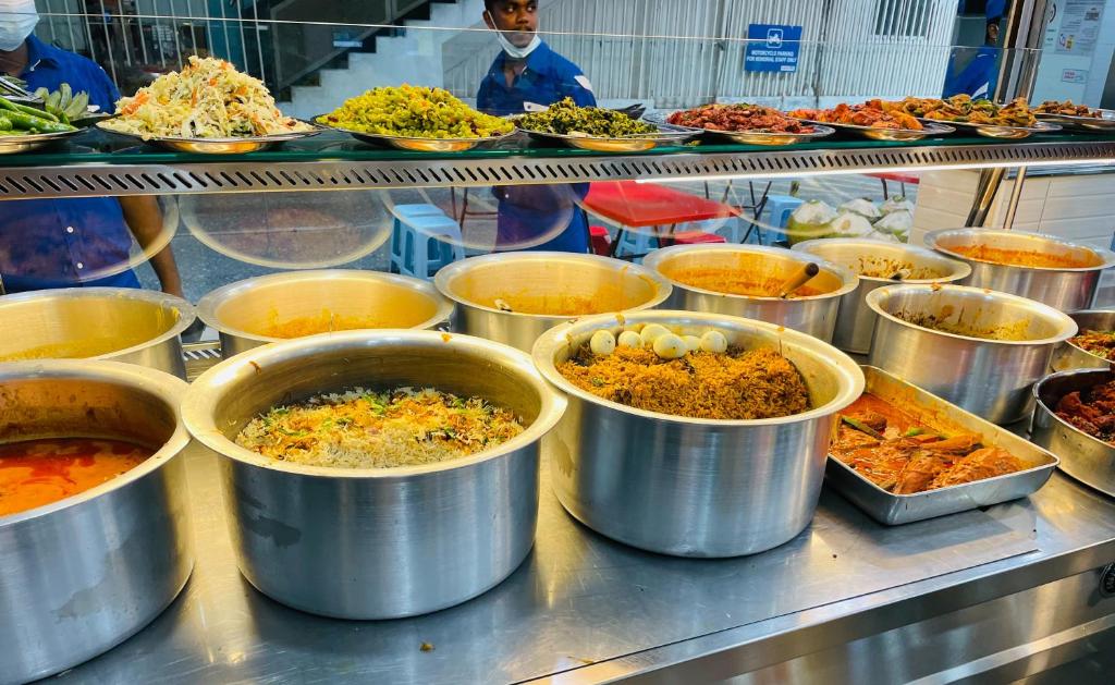Large pots and trays of prepared dishes fill an open restaurant food counter.