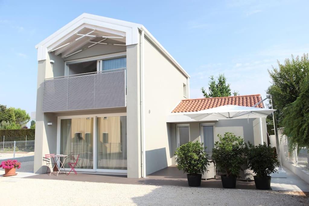 a white house with an umbrella and potted plants at Elegant house with a garden in Mira