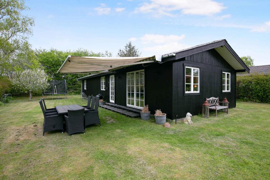 a black tiny house in a yard at Nyistandsat sommerhus med kærlighed og sjæl in Kyndeløse