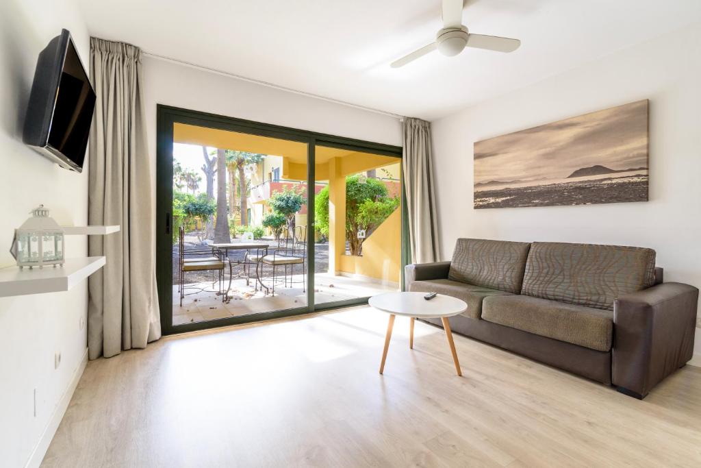 uma sala de estar com um sofá e uma mesa em Apartment in resort em Corralejo