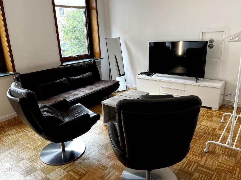 een woonkamer met 2 stoelen en een televisie bij EXKLUSIVE Wohnung mitten im schönsten Viertel in Bremen