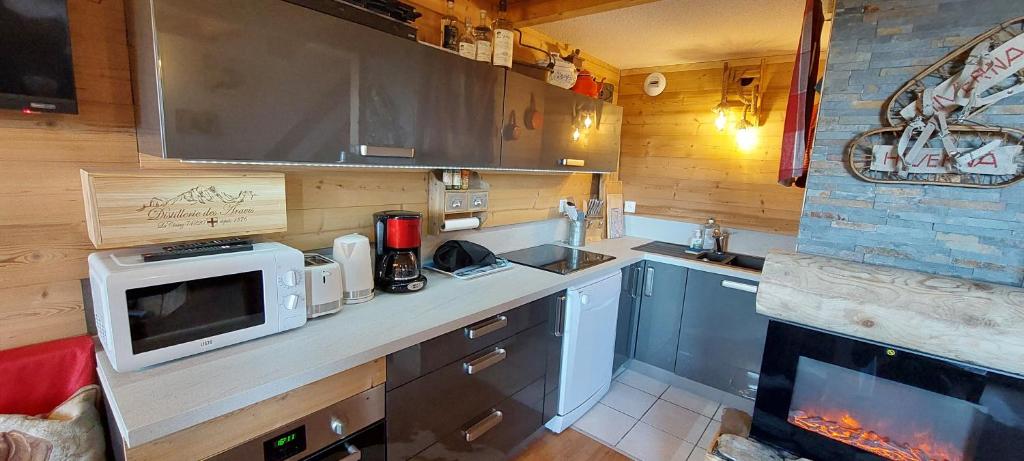 a kitchen with a microwave oven and a fireplace at Bal2502 in Manigod