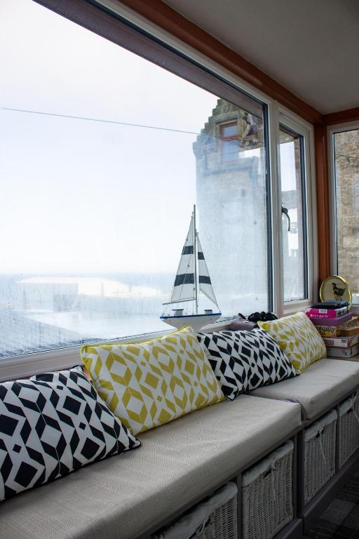 a bench with pillows on it in front of a window at Kintrae B&B in Buckie