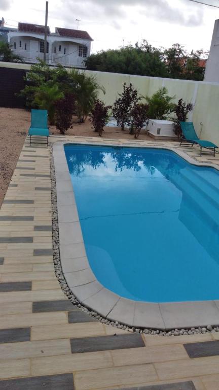 a blue swimming pool with two chairs next to a building at Bungalow at Pereybere in Grand-Baie