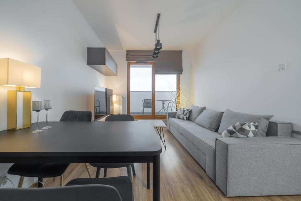a living room with a gray couch and a table at Apartament Kapitalny in Gdańsk