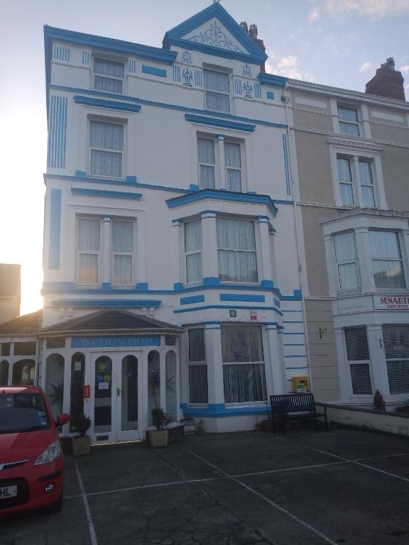 een groot wit gebouw met een auto ervoor geparkeerd bij Wedgwood Guest House in Llandudno