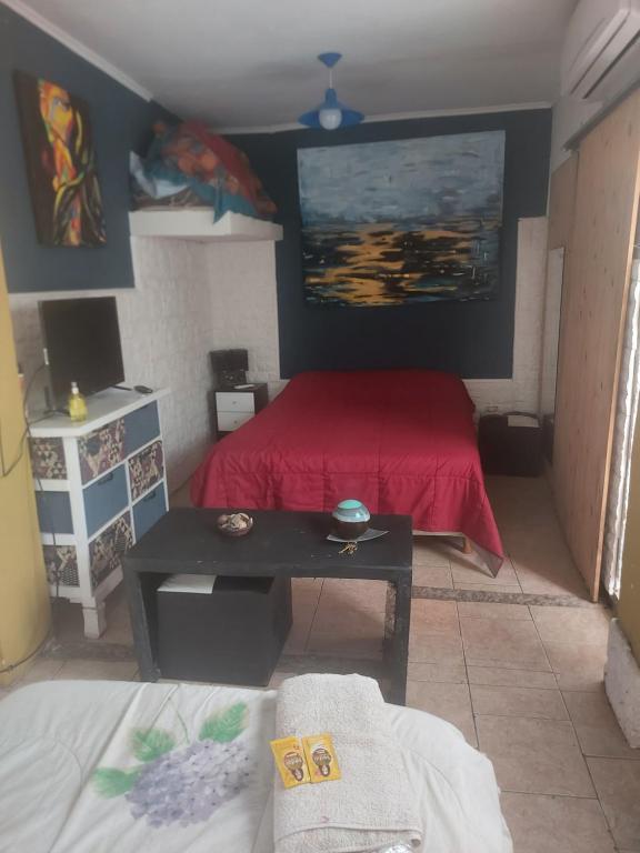 a bedroom with a red bed and a table at LA CASA DE CLAU in Sarandí