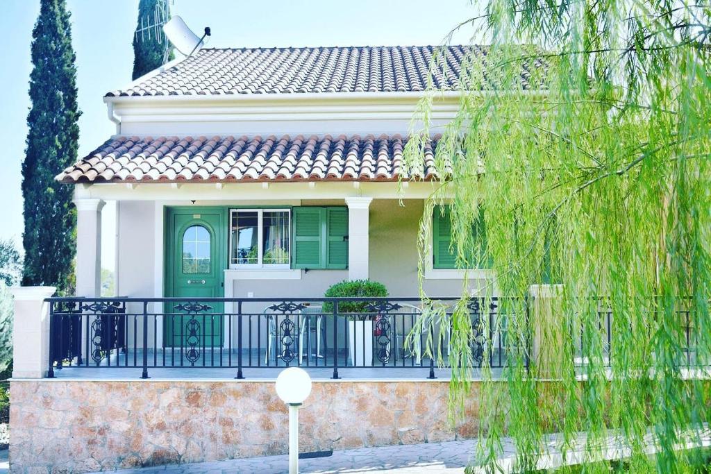 ein Haus mit einer grünen Tür und einem Balkon in der Unterkunft Spyridoula Resort Hotel in Corfu in Gouvia