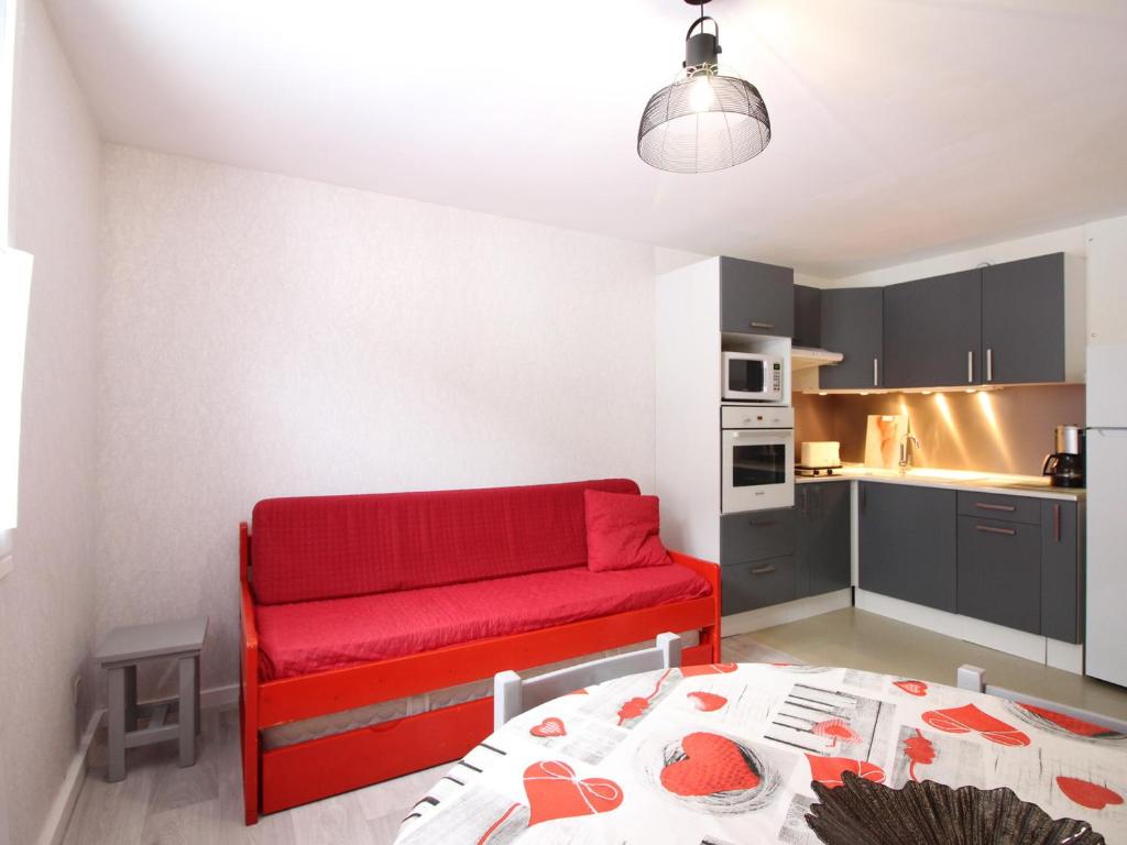 un salon avec un canapé rouge et une cuisine dans l'établissement T2 Mont-Dore 32m², Ascenseur, Parking, Calme, Proche Centre & Thermes - FR-1-608-91, à Le Mont-Dore