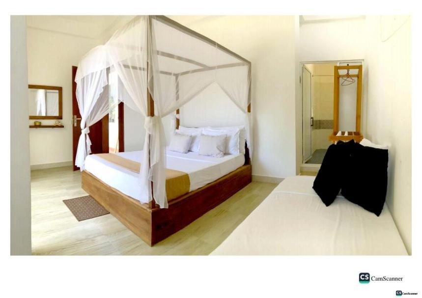 KatuneriyaにあるAyona Beach Villaのベッドルーム(天蓋付きベッド1台、鏡付)