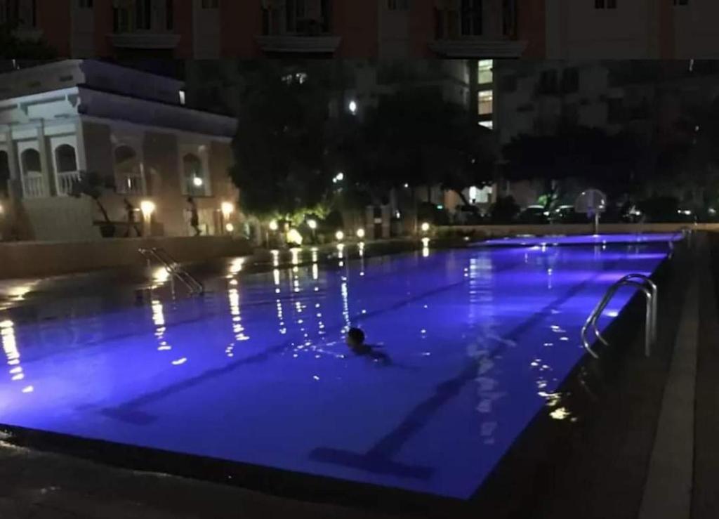 - une grande piscine avec éclairage bleu la nuit dans l'établissement CHATEAU ELYSEE A13 Near Resto And Sm Mall/Airport, à Manille