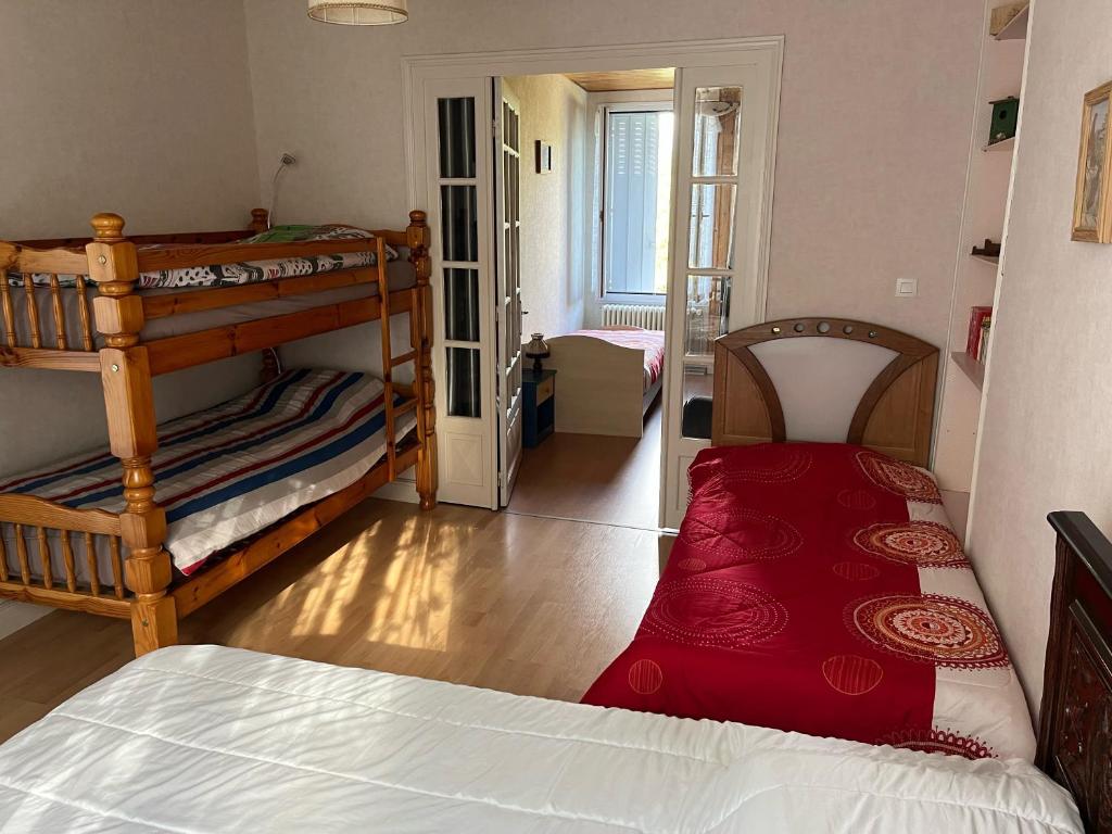 a bedroom with two bunk beds with a red blanket at Entre mûres et châtaignes in Les Châtelliers-Châteaumur