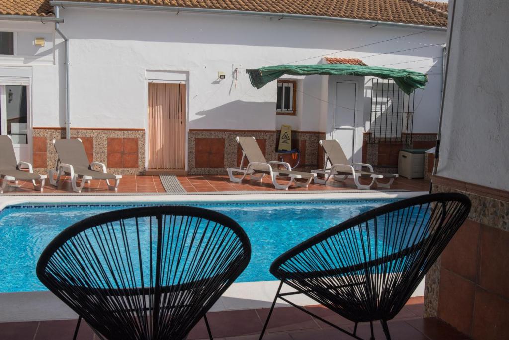 a swimming pool with two chairs and an umbrella at Holiday Home El Patio in Fuente de Piedra
