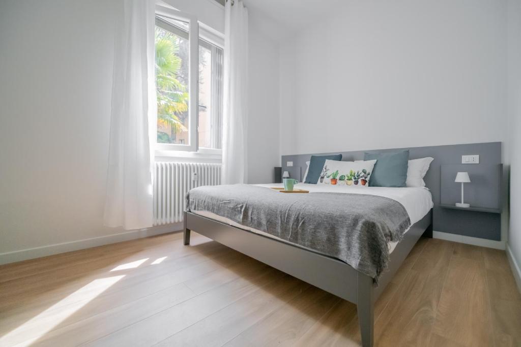 a white bedroom with a bed and a window at Realkasa La Pigna Flat in Bologna